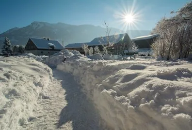 Verschneiter Weg zwischen den Häusern in Meisten, tief stehende Wintersonne