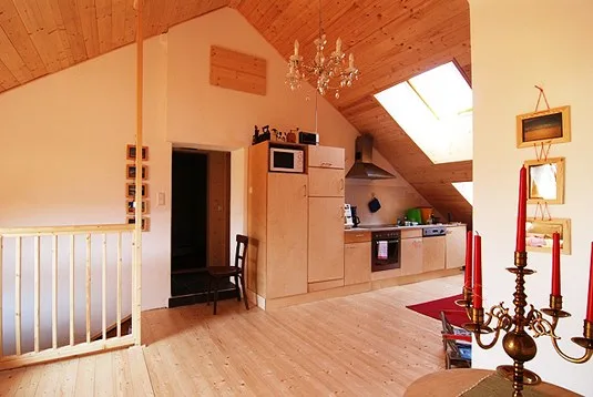 Offener Wohnbereich unter der Dachschräge mit Luster, Holzdecke und Treppengeländer