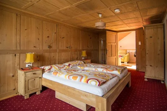 Schlafzimmer mit alten Holzkassetten-Wänden, Doppelbett und rotem Teppich